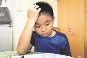 Tay Danzel, 10 trying to concentrate on his homework. More than a third of lower primary school pupils are not getting enough sleep, but only 8 per cent of parents recognise that their child may have sleep problems. -- ST PHOTO: CHEW SENG KIM